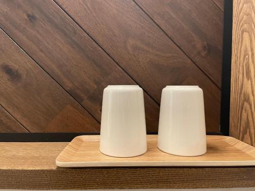 two white vases sitting on a wooden tray at Hotel Yuzuki in Takamatsu
