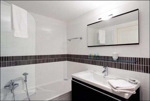 une salle de bain blanche avec un lavabo et un miroir dans l'établissement Sunlight Properties - Bugatti - Beausoleil, France 1 Bedroom, stunning holiday rental apartment with balcony, à Beausoleil