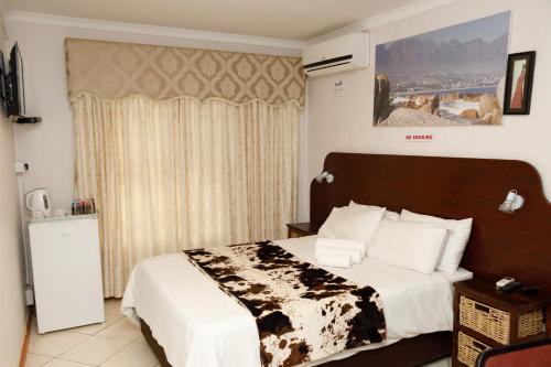 een slaapkamer met een bed met een zwart-witte deken bij Rainbow Guest House and Tours in Uitenhage