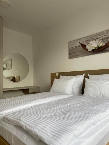 a bed with white sheets and a painting on the wall at Alpine Haven in Bovec