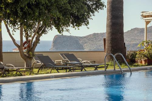 a swimming pool with lounge chairs next to the ocean at Chrissida Hotel in Nea Kydonia