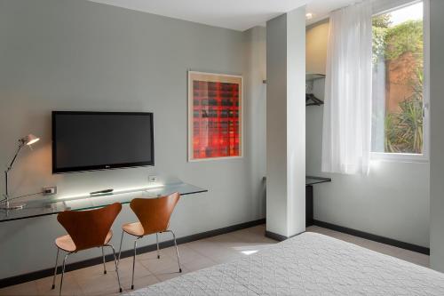 a room with two chairs and a television on a wall at Hotel Verona in Verona