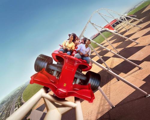 three people riding a red car on a roller coaster at Hilton Abu Dhabi Yas Island in Abu Dhabi