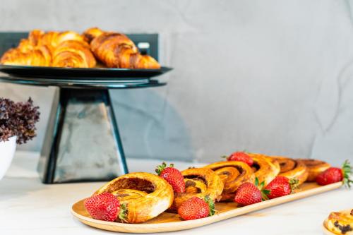 a plate of pastries and strawberries on a table at Stuart Rooms by Zzzing in Il-Gżira