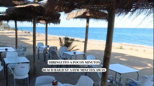 a beach with tables and chairs and the ocean at Duplex Mojácar Beach in Mojácar