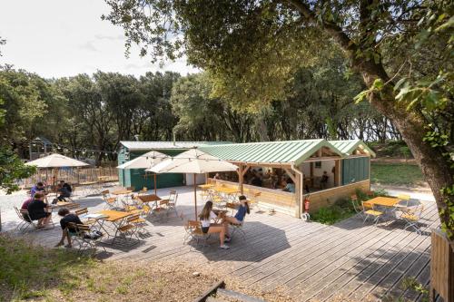 un groupe de personnes assises à des tables sur une terrasse dans l'établissement Huttopia Oléron Les Chênes Verts, à Dolus-d'Oléron
