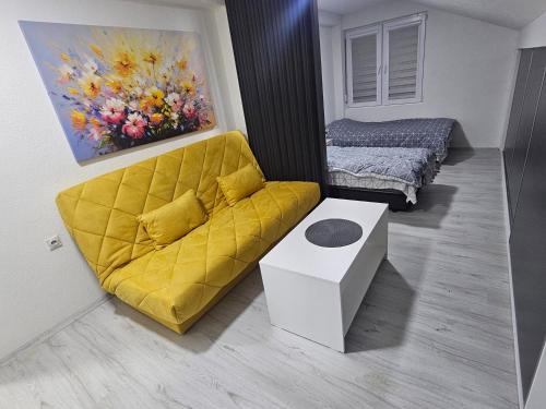 a living room with a yellow couch and a painting at East Gate Apartments in Kriva Palanka