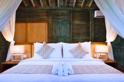 a bed with a blue stuffed animal sitting on it at Putri Malu 3 BR Share Pool JU33 in Keramas