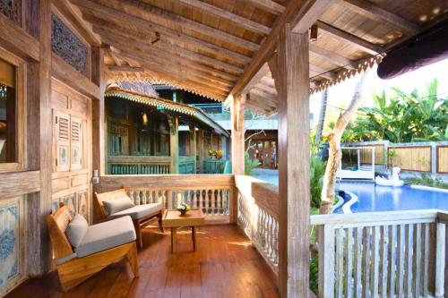 a porch of a house with a swimming pool at Putri Malu 3 BR Share Pool JU33 in Keramas