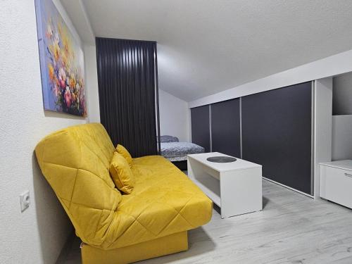 a living room with a yellow chair and a table at East Gate Apartments in Kriva Palanka