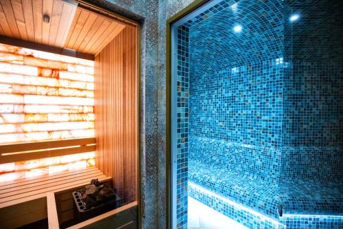 W łazience znajduje się prysznic ze ścianą wyłożoną niebieskimi kafelkami. w obiekcie Hotel Foisorul cu Flori w mieście Sinaia