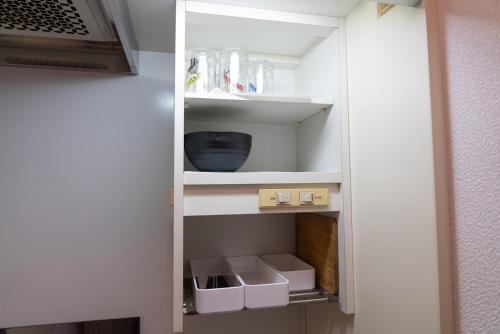 a white pantry with some boxes and dishes in it at いちょう坂ゲストハウス in Mito