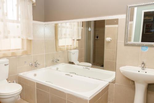 een badkamer met een bad, een toilet en een wastafel bij Rainbow Guest House and Tours in Uitenhage