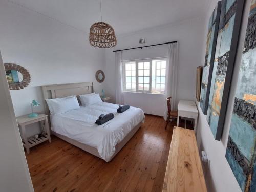 a bedroom with a white bed and a window at St James Mansions Apartment in Muizenberg