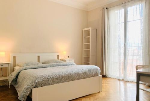 une chambre blanche avec un lit et une grande fenêtre dans l'établissement Chic & Spacious Getaway in Nice - 10min to Beach, à Nice