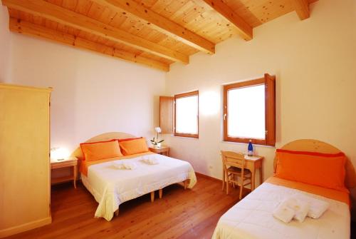 a bedroom with two beds and two windows at Corte all'Olmo in Ca' di David