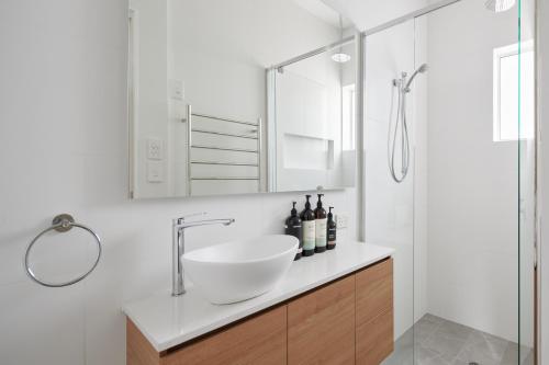Un baño blanco con lavabo y ducha. en Apartment in the Heart of Sandy Bay, en Sandy Bay