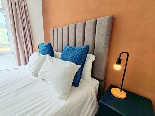 a bedroom with a bed with blue and white pillows at Beach Hut Empire Apartment in Muizenberg