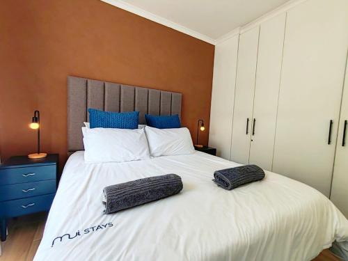 a bedroom with a large bed with two pillows on it at Beach Hut Empire Apartment in Muizenberg
