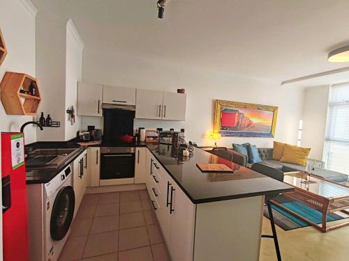 a kitchen with a stove top oven next to a couch at Beach Hut Empire Apartment in Muizenberg