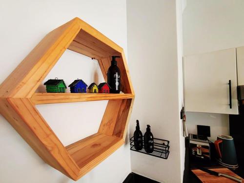 a wooden shelf on a wall with wine bottles at Beach Hut Empire Apartment in Muizenberg