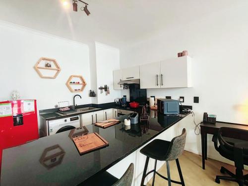 a kitchen with a black counter top and a red refrigerator at Beach Hut Empire Apartment in Muizenberg