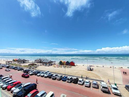a parking lot with cars parked at the beach at Beach Hut Empire Apartment in Muizenberg