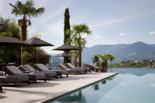 einen Pool mit Liegestühlen und Sonnenschirmen neben dem Wasser in der Unterkunft Feel good Resort Johannis in Dorf Tirol
