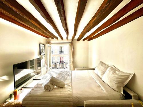 une chambre avec un grand lit avec un plafond en bois dans l'établissement Le perchoir - Charmant & Lumineux - Bastille, à Paris