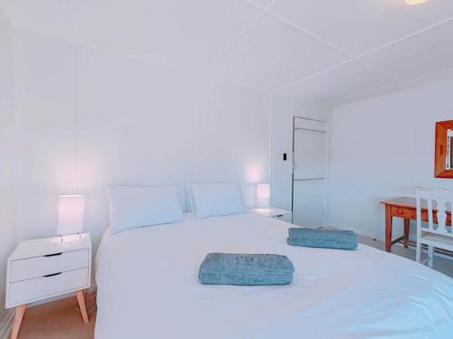 a bedroom with a white bed with two pillows on it at Timber's Ocean House in Simonʼs Town