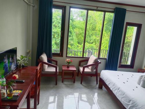 1 dormitorio con 1 cama, escritorio y ventanas en Dokchampa Hotel en Vang Vieng