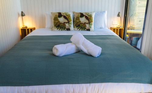 a bed with two white socks on a green blanket at Kukupa Puni at Akaroa Lavender in Duvauchelle