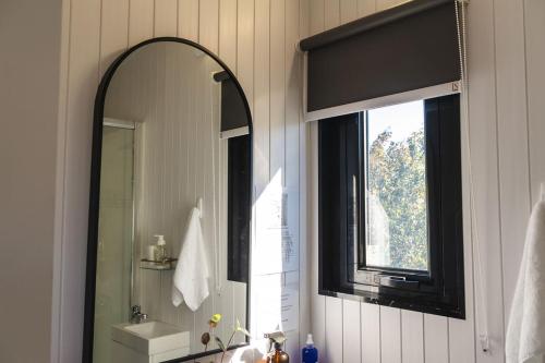 a bathroom with a mirror and a sink and a window at Kukupa Puni at Akaroa Lavender in Duvauchelle