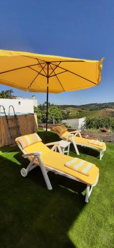 three lounge chairs and an umbrella on the grass at Landal House - Óbidos 