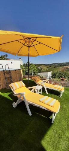 three lounge chairs and an umbrella on the grass at Refúgio no Oeste com Vistas Perto Óbidos e Praias in Landal