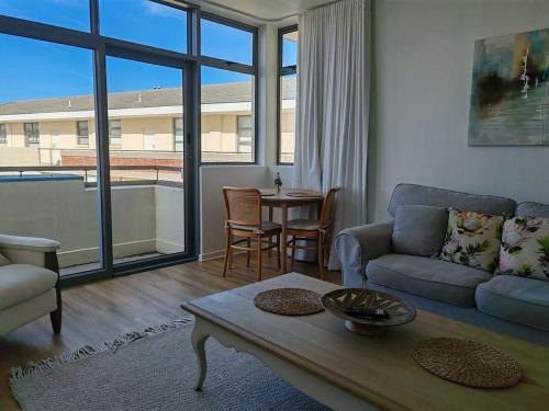 a living room with a couch and a table at Courtside Views Empire Apartment in Muizenberg