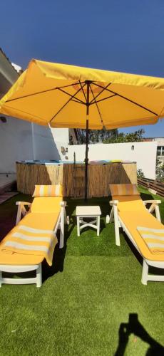 two lounge chairs and an umbrella on the grass at Landal House - Óbidos 