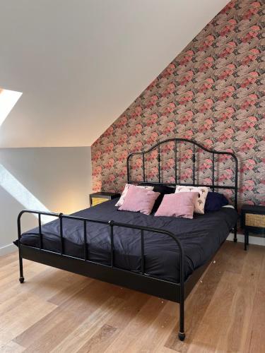 - un lit noir avec des oreillers roses dans une chambre dans l'établissement La grange - Grande longère à moins de 30 minutes des plages, à Plumelec