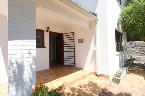 a white house with a door and a patio at Annies Place Muizenberg in Muizenberg