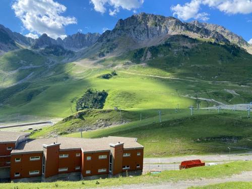 un bâtiment sur une colline avec une montagne en arrière-plan dans l'établissement La Mongie - T2 4 à 6 personnes, 45m2 face aux pistes, à Bagnères-de-Bigorre