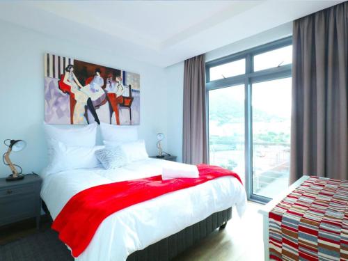 Un dormitorio con una cama con una manta roja. en Sea Life Muizenberg, en Muizenberg