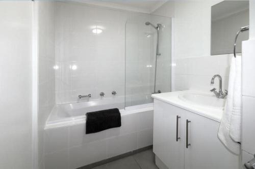 ein weißes Badezimmer mit einer Badewanne und einem Waschbecken in der Unterkunft Sea Life Muizenberg in Muizenberg