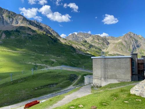 un bâtiment sur une colline avec des montagnes en arrière-plan dans l'établissement La Mongie - T2 4 à 6 personnes, 45m2 face aux pistes, à Bagnères-de-Bigorre