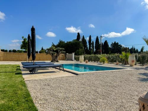 - une piscine avec deux bancs bleus à côté d'une cour dans l'établissement Villas Les Plaines en Provence, à Maillane