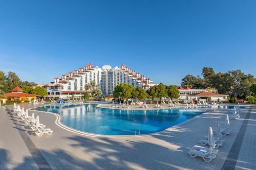 a large swimming pool with chairs and a hotel at Green Max Hotel in Belek