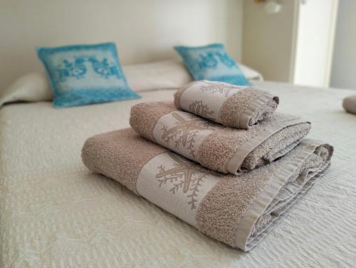 un mucchio di asciugamani seduti sopra un letto di Appartamento La Terrazza - Località Cala Gavetta a La Maddalena