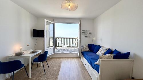 un salon avec un canapé bleu et une grande fenêtre dans l'établissement Panorama, studio vue sur mer, au Crotoy