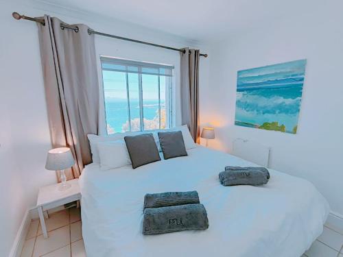 a bedroom with a white bed with two towels on it at Bay Views in Simonʼs Town