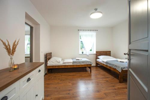 a room with two beds and a kitchen with wooden floors at Apartmány Vilka Orlík in Teplice nad Metují