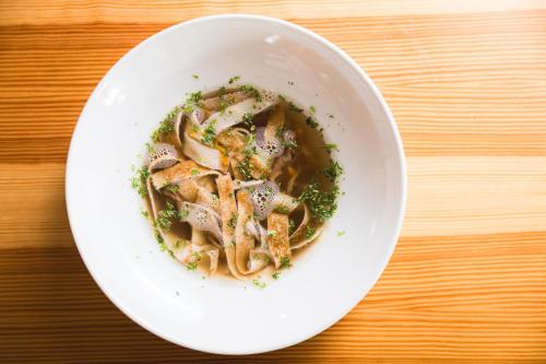 a bowl of soup with meat and herbs on a wooden table at Apartmány Vilka Orlík in Teplice nad Metují